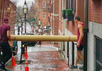 Two men from Fallen Movers move a carpet from a house